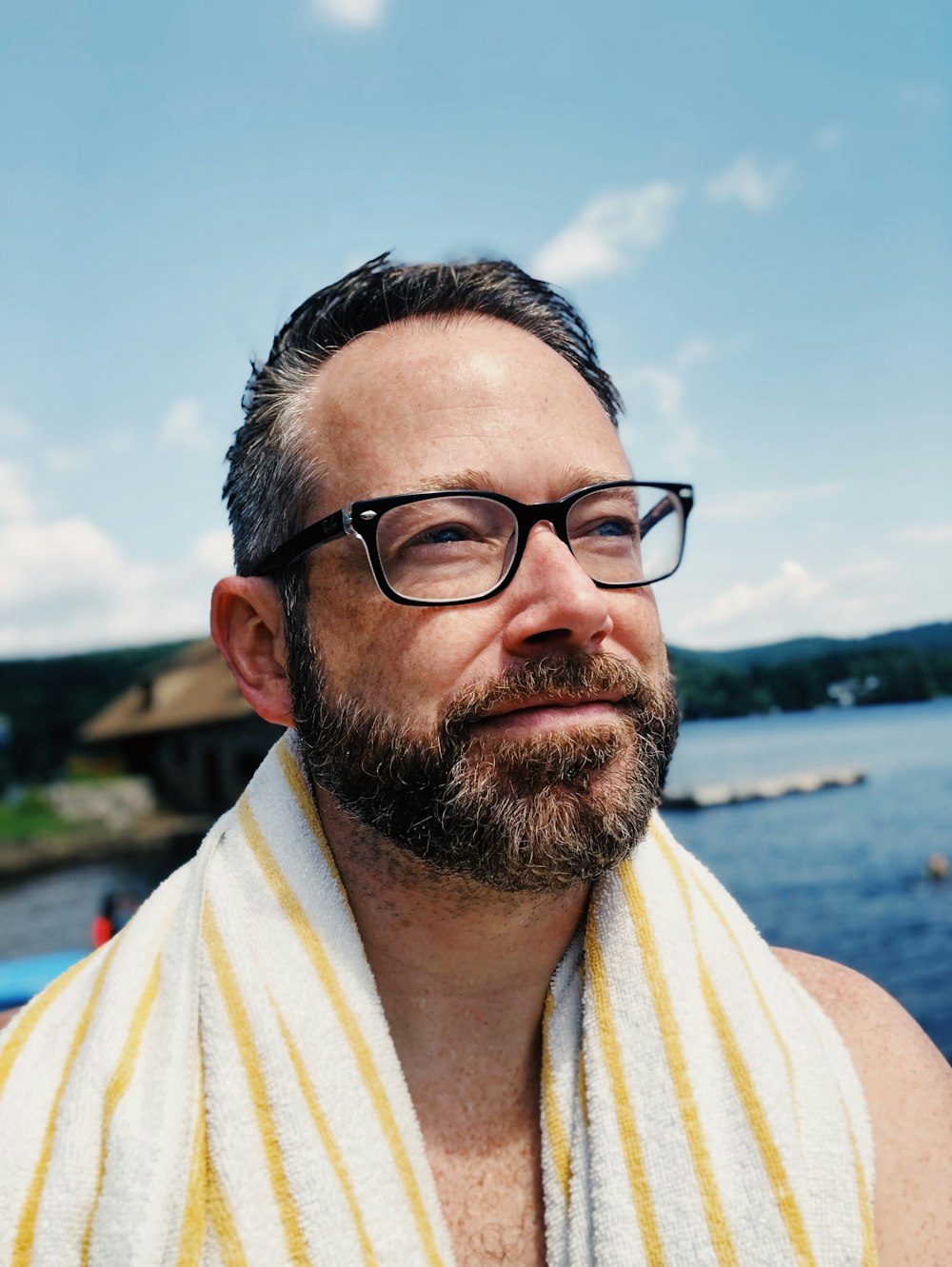 man wearing eyeglasses with white and yellow towel on his neck