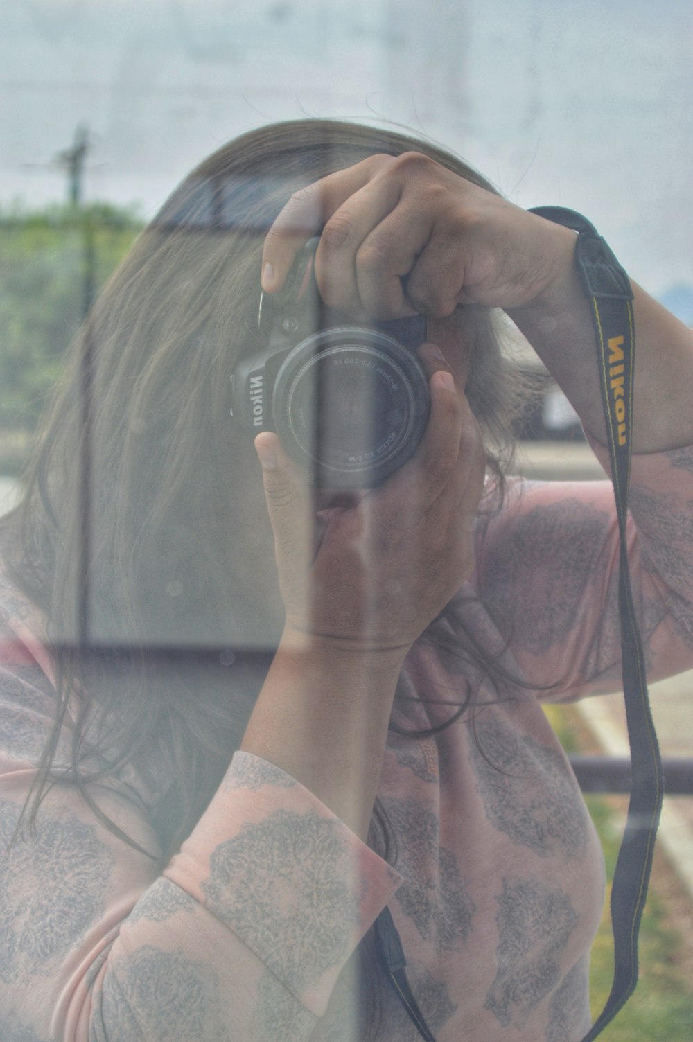 woman wearing pink long-sleeved blouse using black Nikon DSLR camera