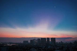 An elegant depiction of planetary orbits overlaying a city skyline at dusk.