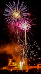 a large fireworks display with a castle in the background