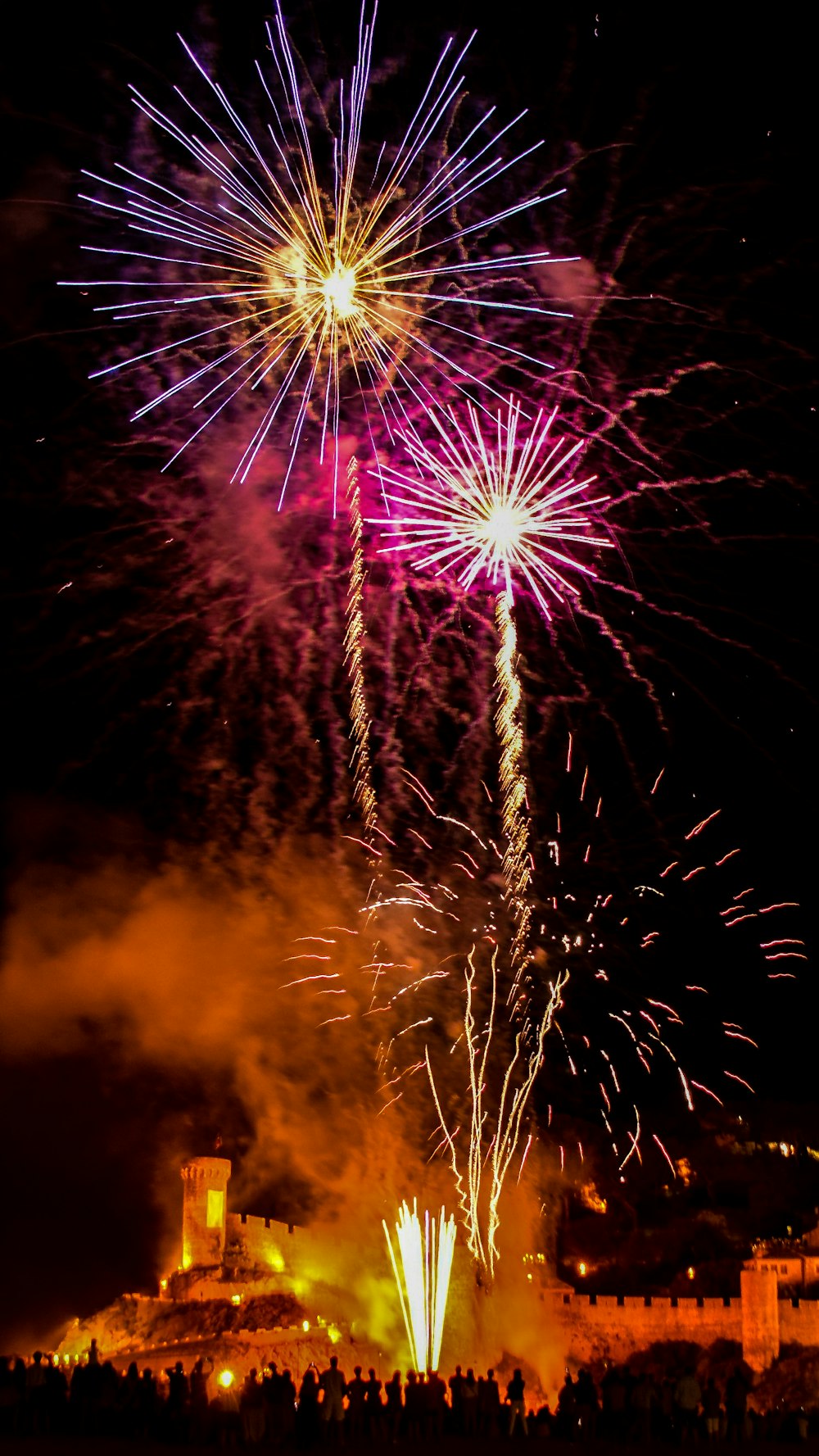 uma grande queima de fogos com um castelo ao fundo