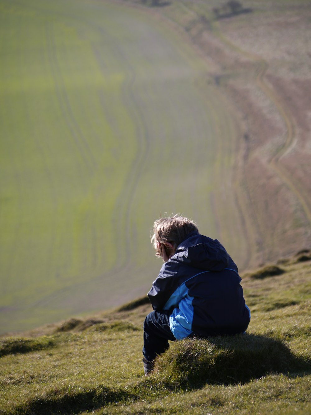 a person sitting on top of a grass covered hill
