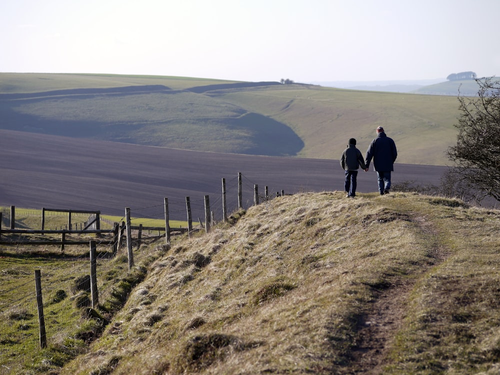 man and boy walking on dirt road during daytime