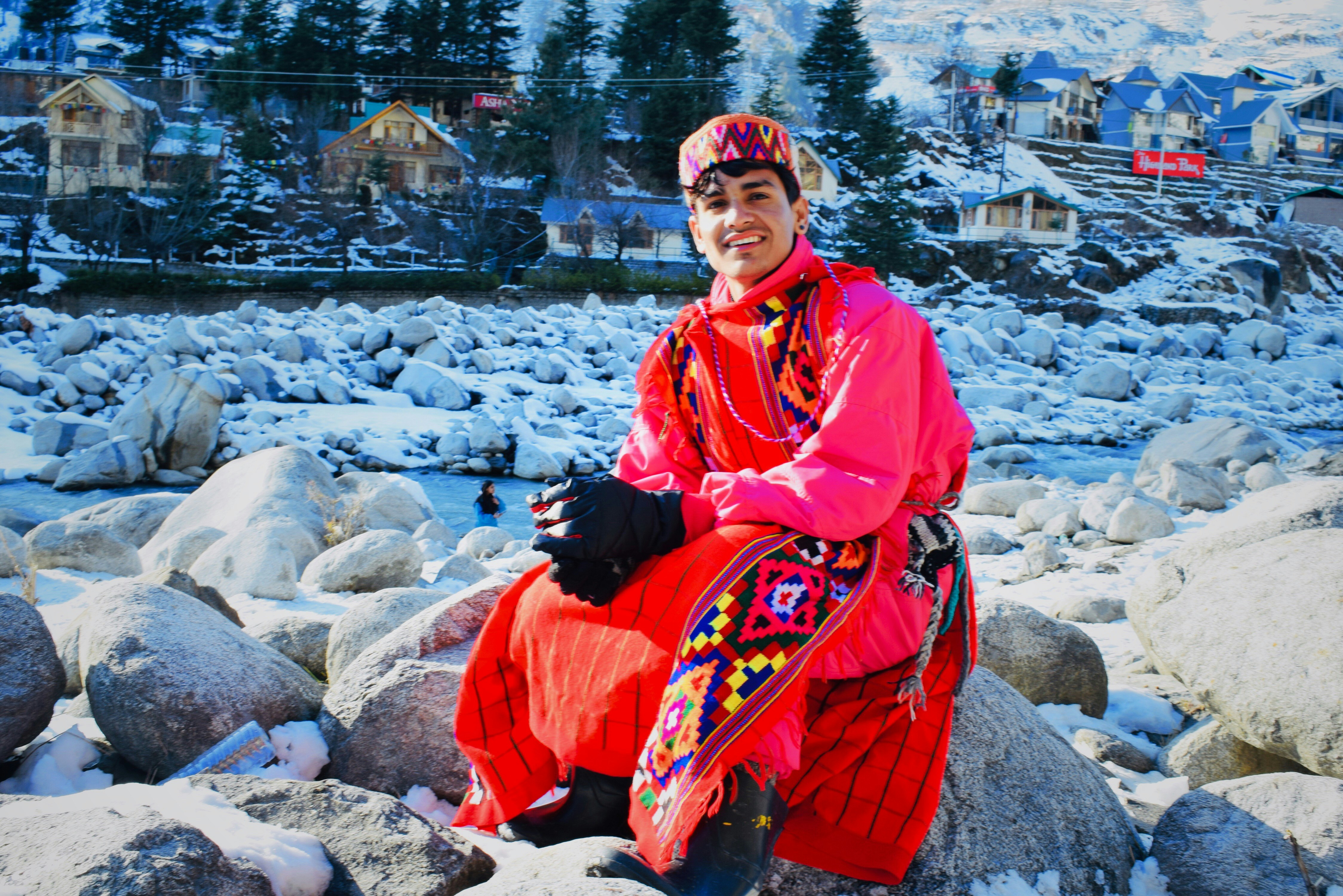 A white curtain being held up around a sitting person, with security personnel visible in the background, near a makeshift protest site in a snowy mountain region.