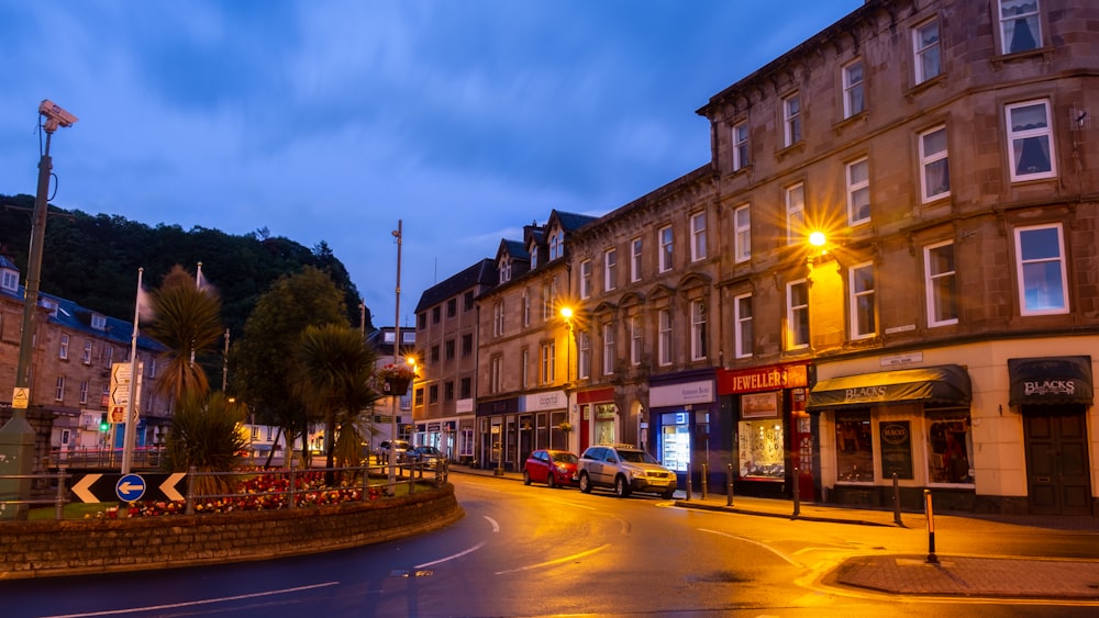 a city street at night with cars parked on the side of the road