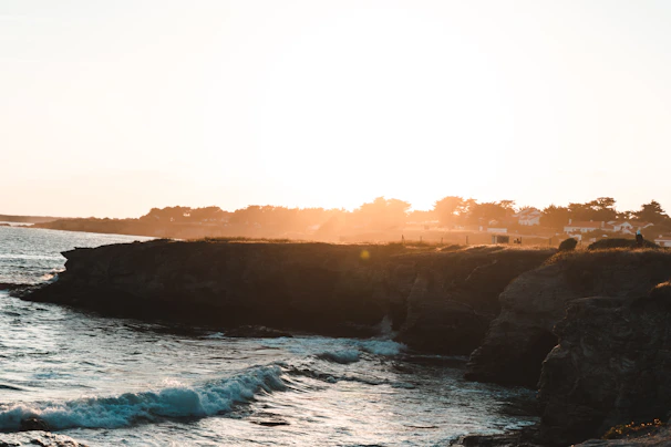 A scenic coastal view at sunset, with warm light casting a soft glow over the waves.