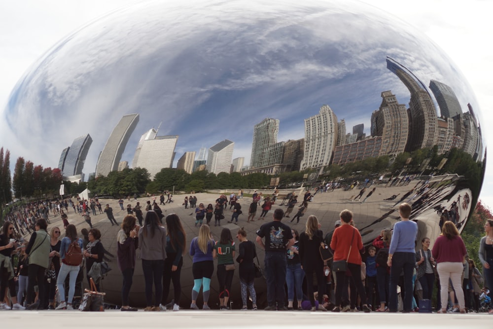 a group of people standing in front of a large metal ball