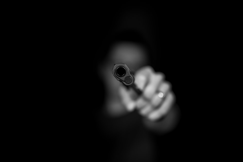Graustufenfotografie einer Person, die eine Waffe hält