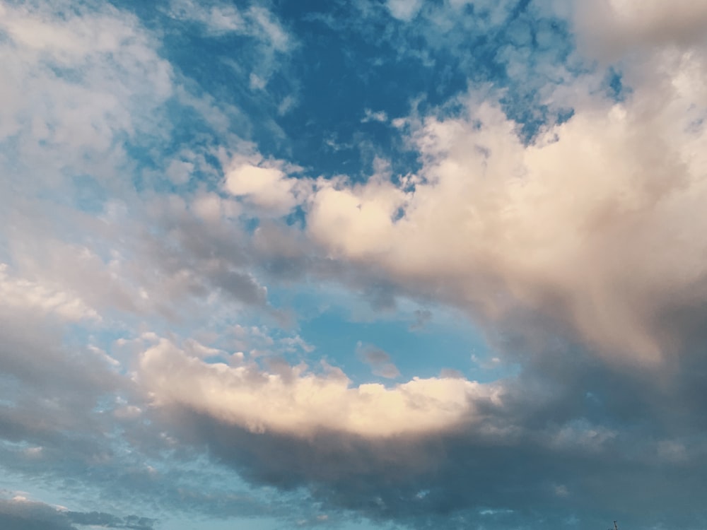 a plane flying through a cloudy blue sky