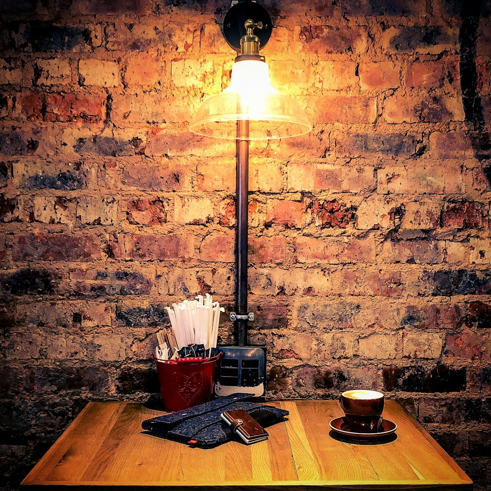 a wooden table topped with a lamp next to a cup of coffee