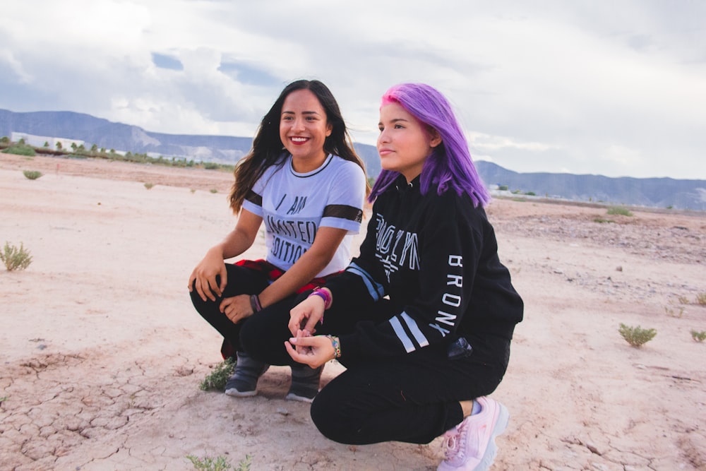 women crouching on sand