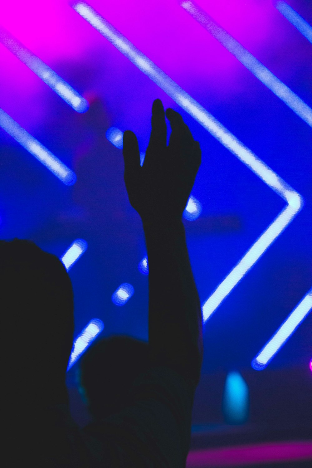 a person raising their hands in front of a stage