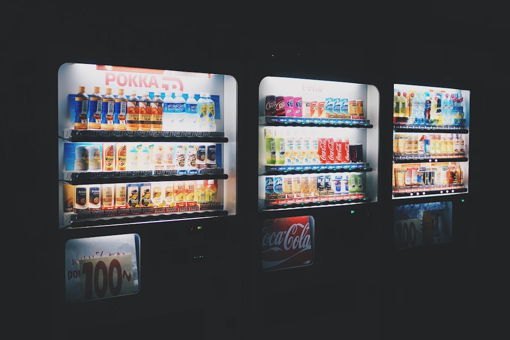três refrigeradores de bebidas comerciais de cores variadas