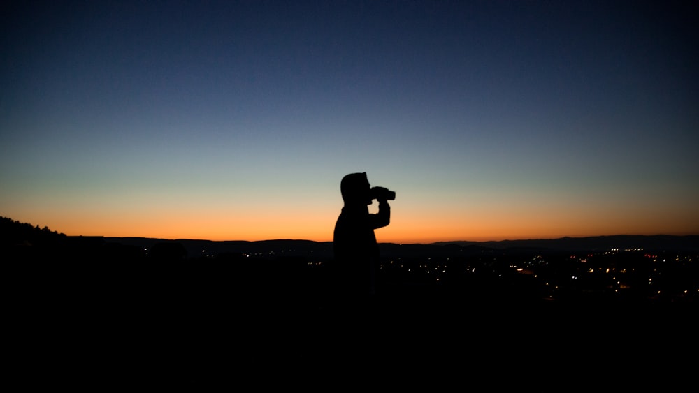 silhouette photo of man about to drink