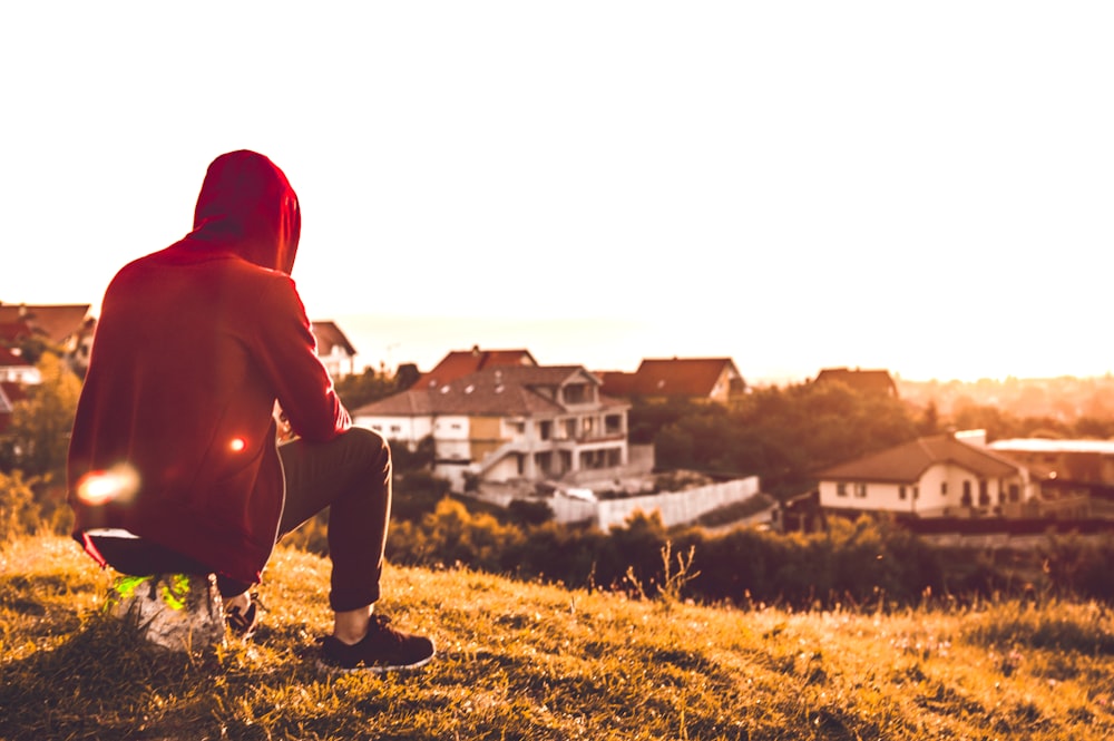 personne assise sur une colline près des maisons pendant la journée