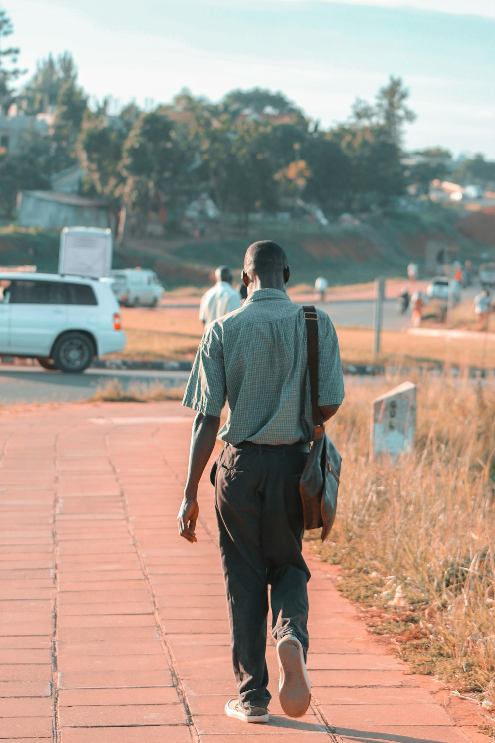 man walking on pathway near road during daytime