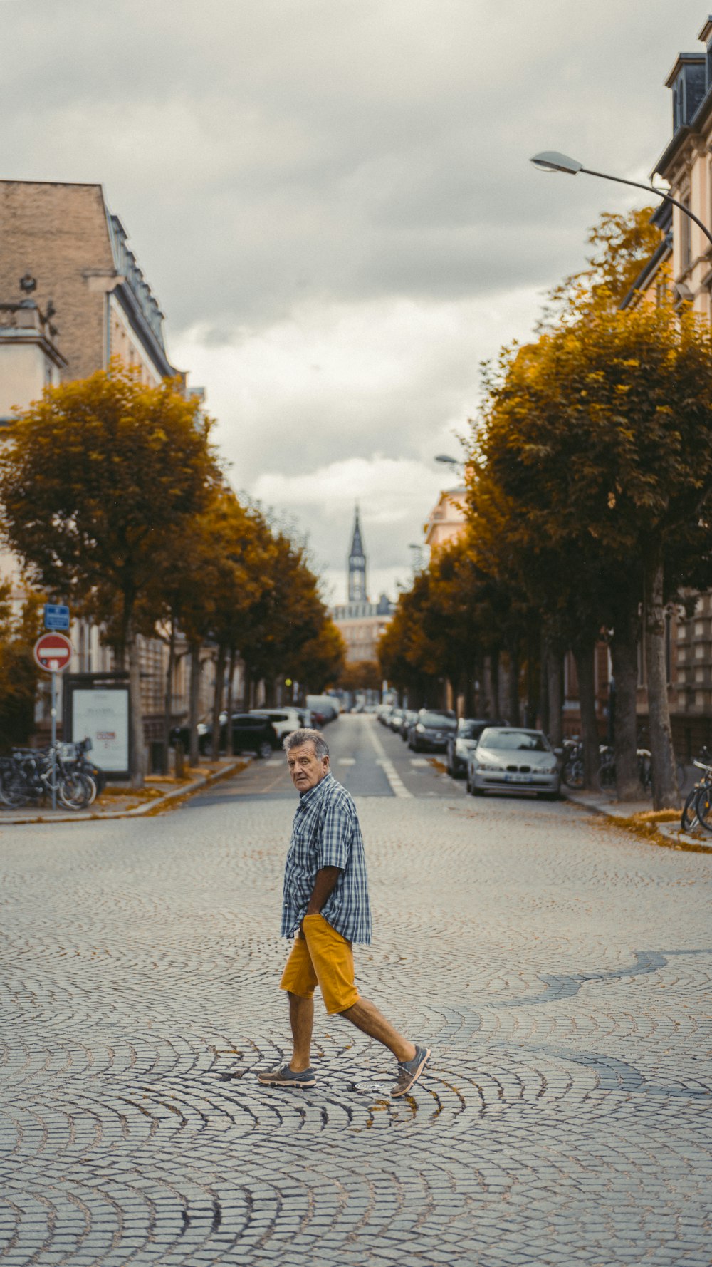 man crossing on pathway near different vehicles parking beside road