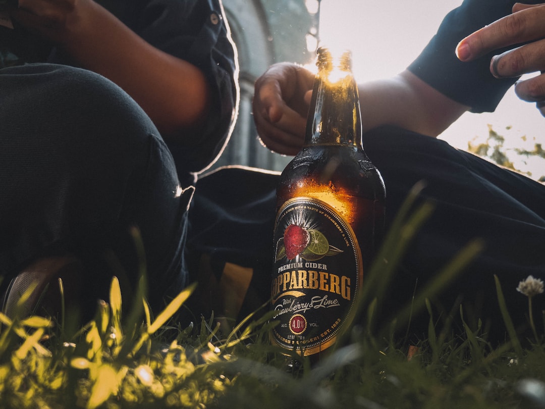 two person sitting on grasses near bottle