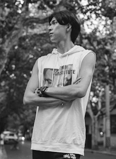 A striking black-and-white photo of a model wearing an oversized demzon hoodie, standing confidently against an urban backdrop at dusk.