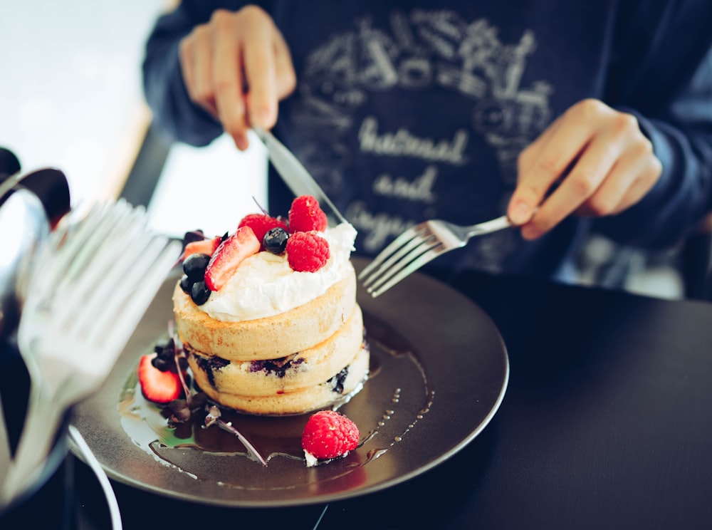 a person cutting a cake with a knife and fork