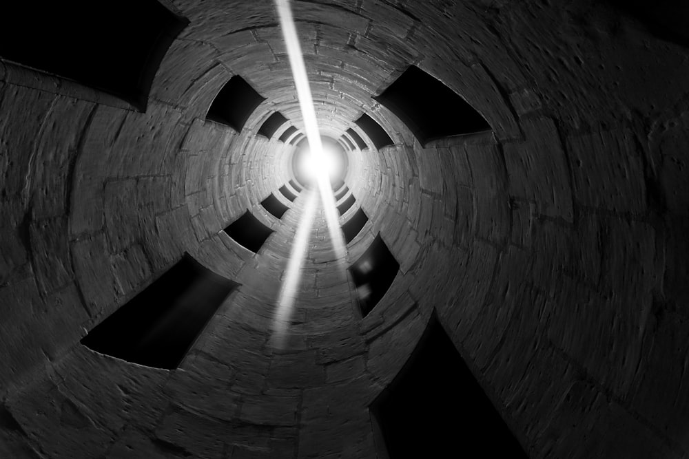 a black and white photo of a light at the end of a tunnel