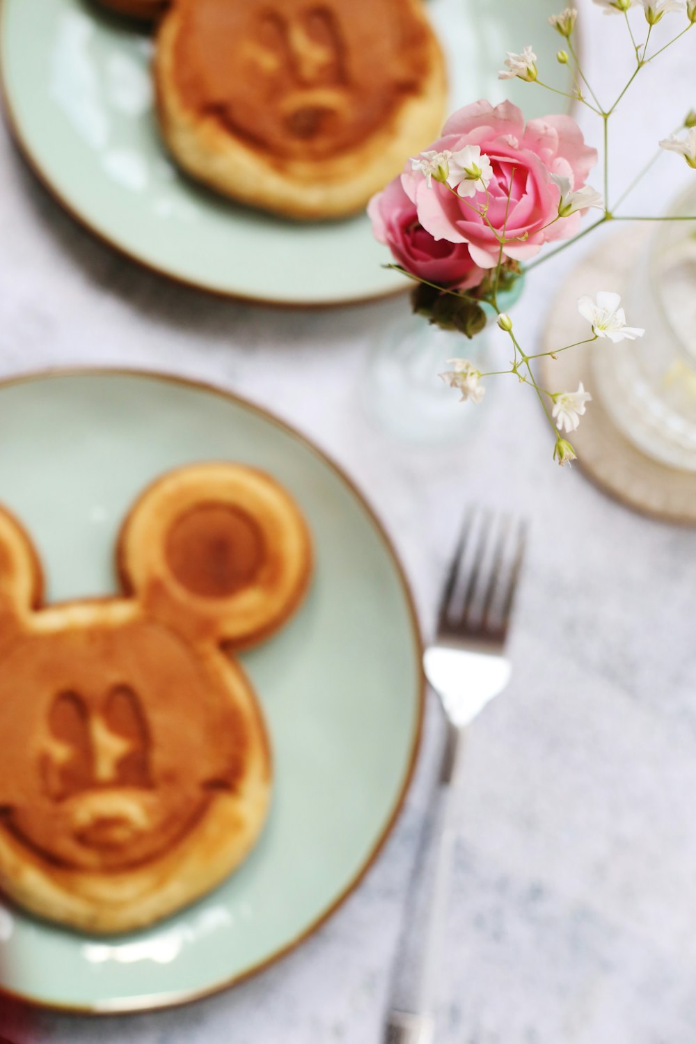 two plates of Mickey Mouse face pancakes on table