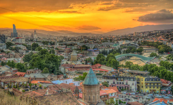 An old town of tiled roofs and church domes under a golden sunset
