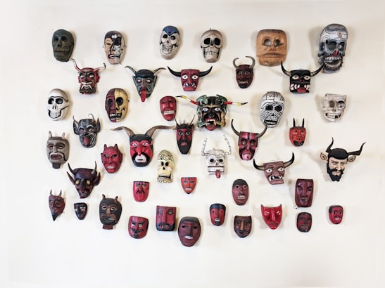 Colorful handcrafted carnival masks displayed on a wooden table with art supplies around.