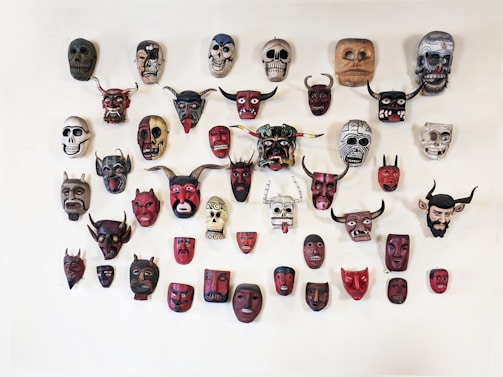 An artistic shot of colorful ritual masks arranged on a neutral background.