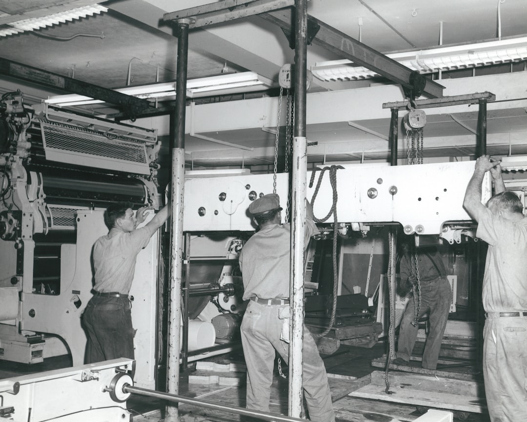 grayscale photo of working people, Installing a brand new press.
