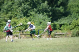 A vibrant college lacrosse field with players in action during a sunny afternoon.