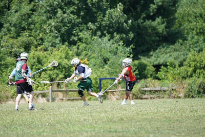 A vibrant college lacrosse field with players in action during a sunny afternoon.