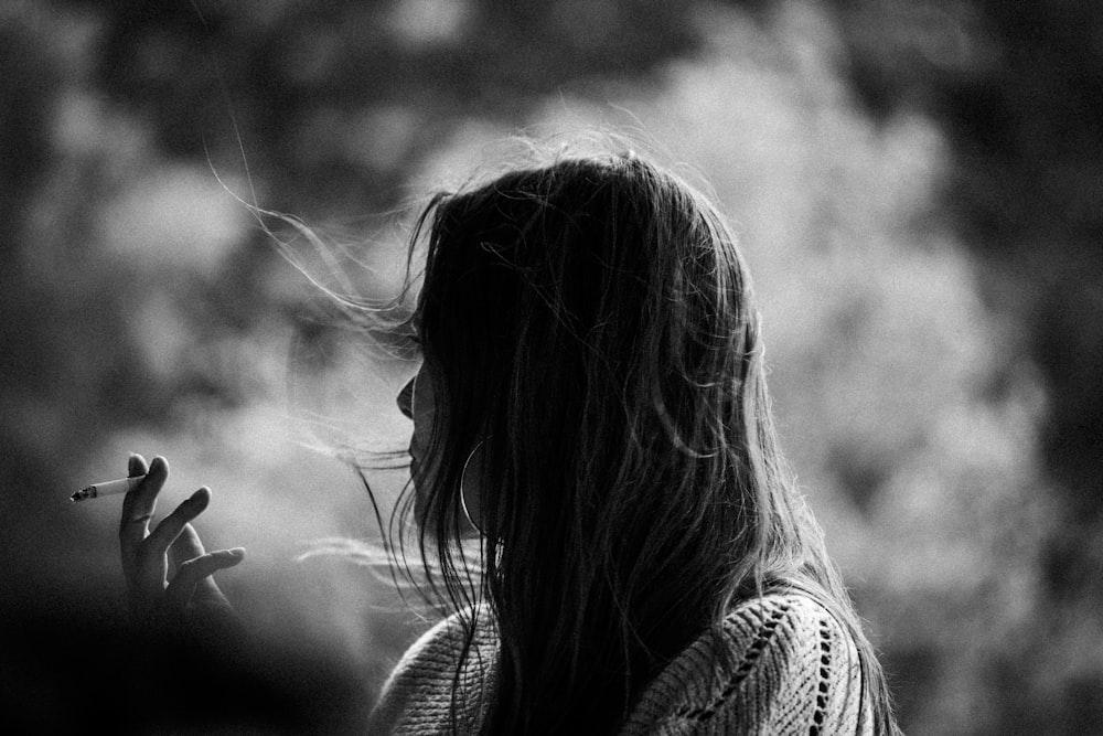 a woman smoking a cigarette in a black and white photo