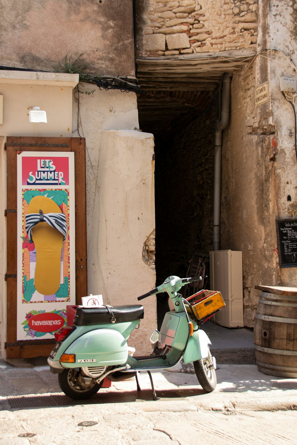 teal motor scooter near brown wooden door