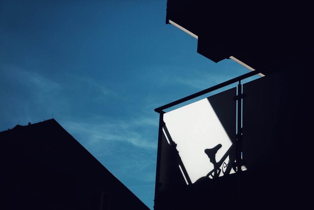 a silhouette of a person on a scaffold against a blue sky