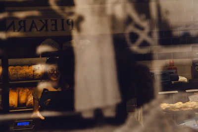 Soft-focus image of a smiling baker arranging pastries in the warm kitchen light.