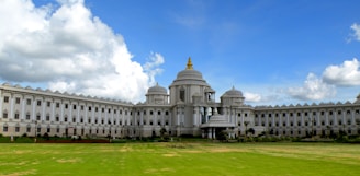 a large white building sitting on top of a lush green field