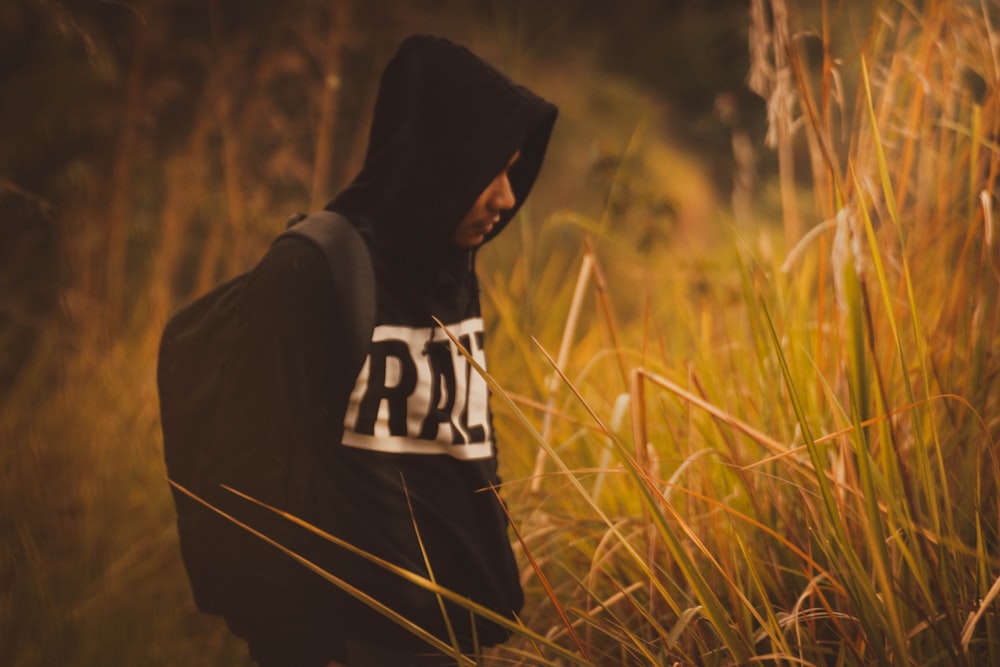 man wearing black and white hoodie standing in front of grass