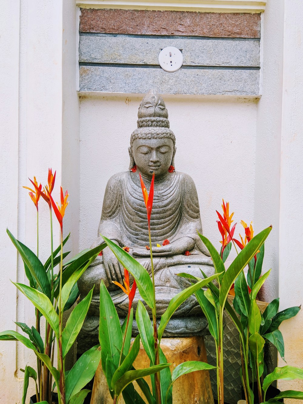 buddha placed on bird's paradise flowers