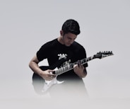 man playing black and white electric guitar