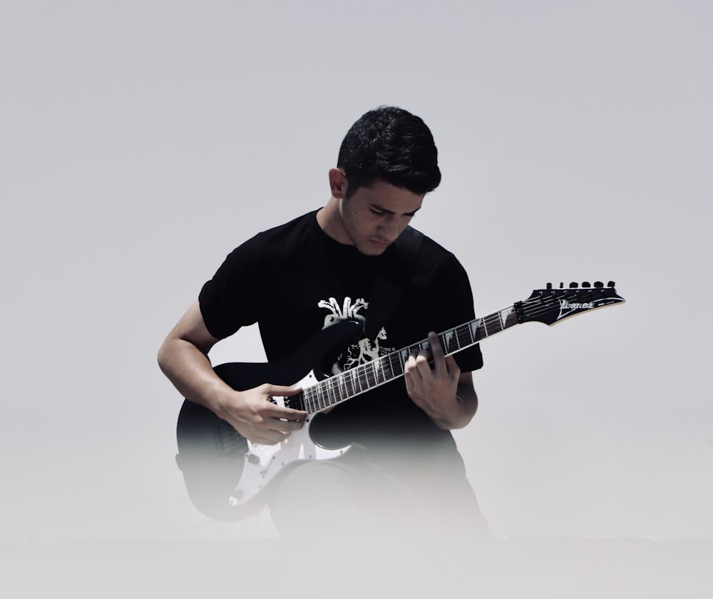 man playing black and white electric guitar