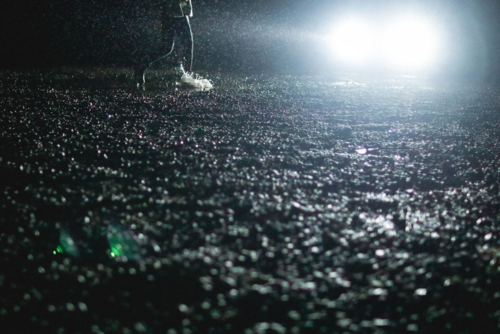 Una persona in piedi sotto la pioggia di notte