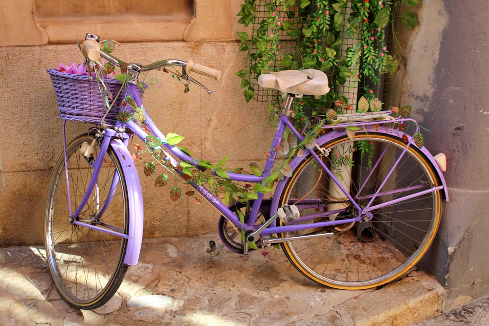 purple city bike parked beside brown wall
