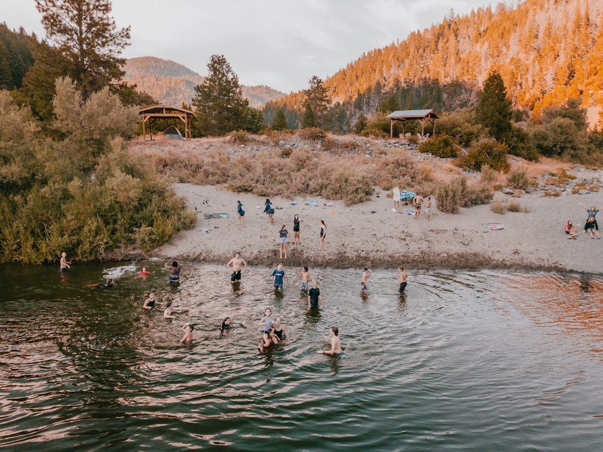 People swimming in a clear river surrounded by rocky hills