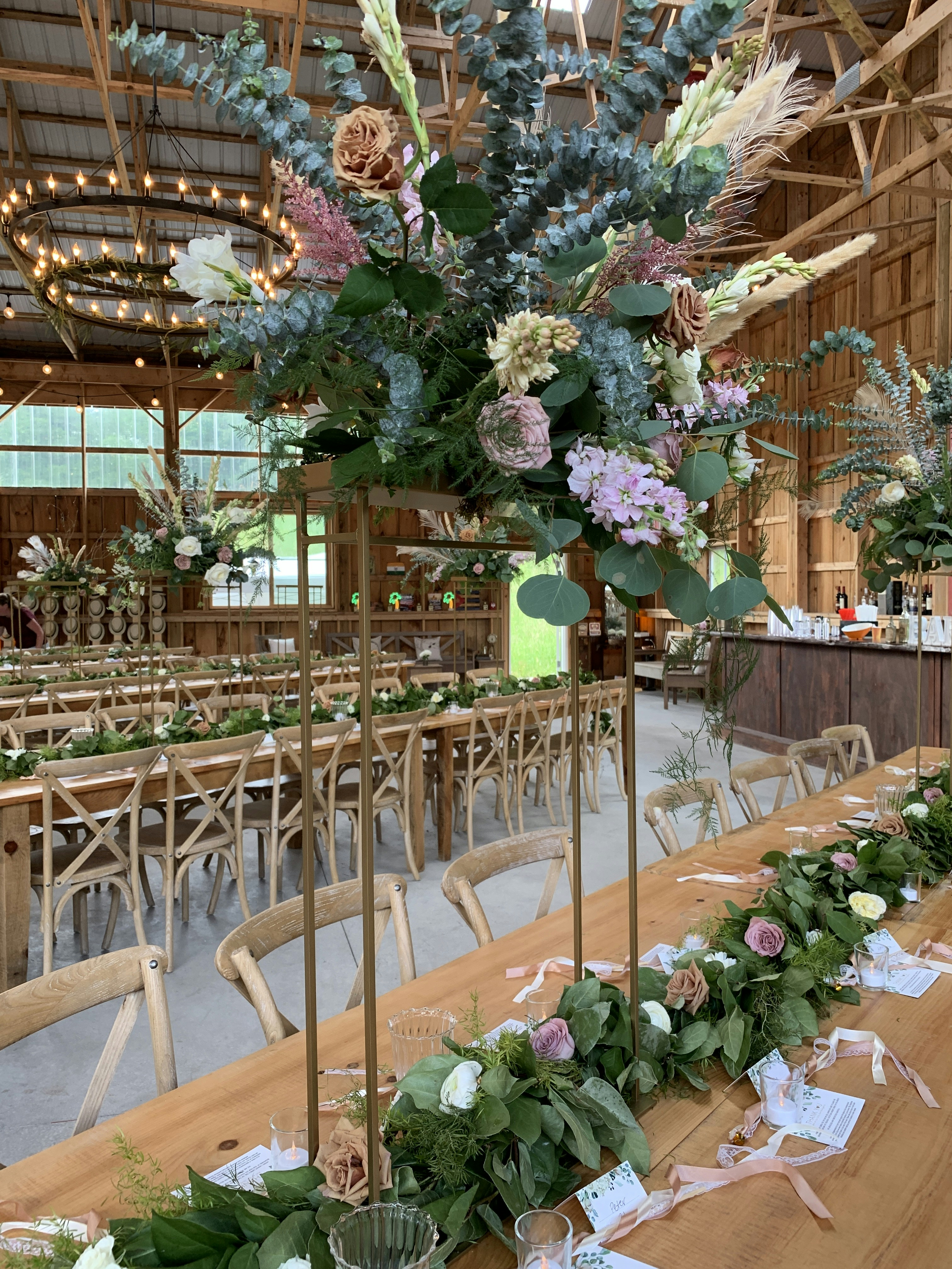 Elegant barn wedding reception with long wooden tables, candles, and wildflower arrangements in warm light