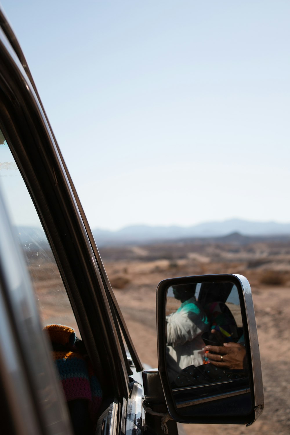 person taking photo of vehicle side mirror