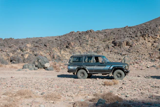 A rugged tour vehicle parked beside a rocky canyon under a clear blue sky