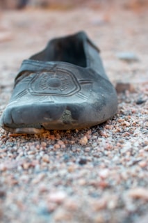 Close-up of worn running shoes resting on a rocky path after a long run.