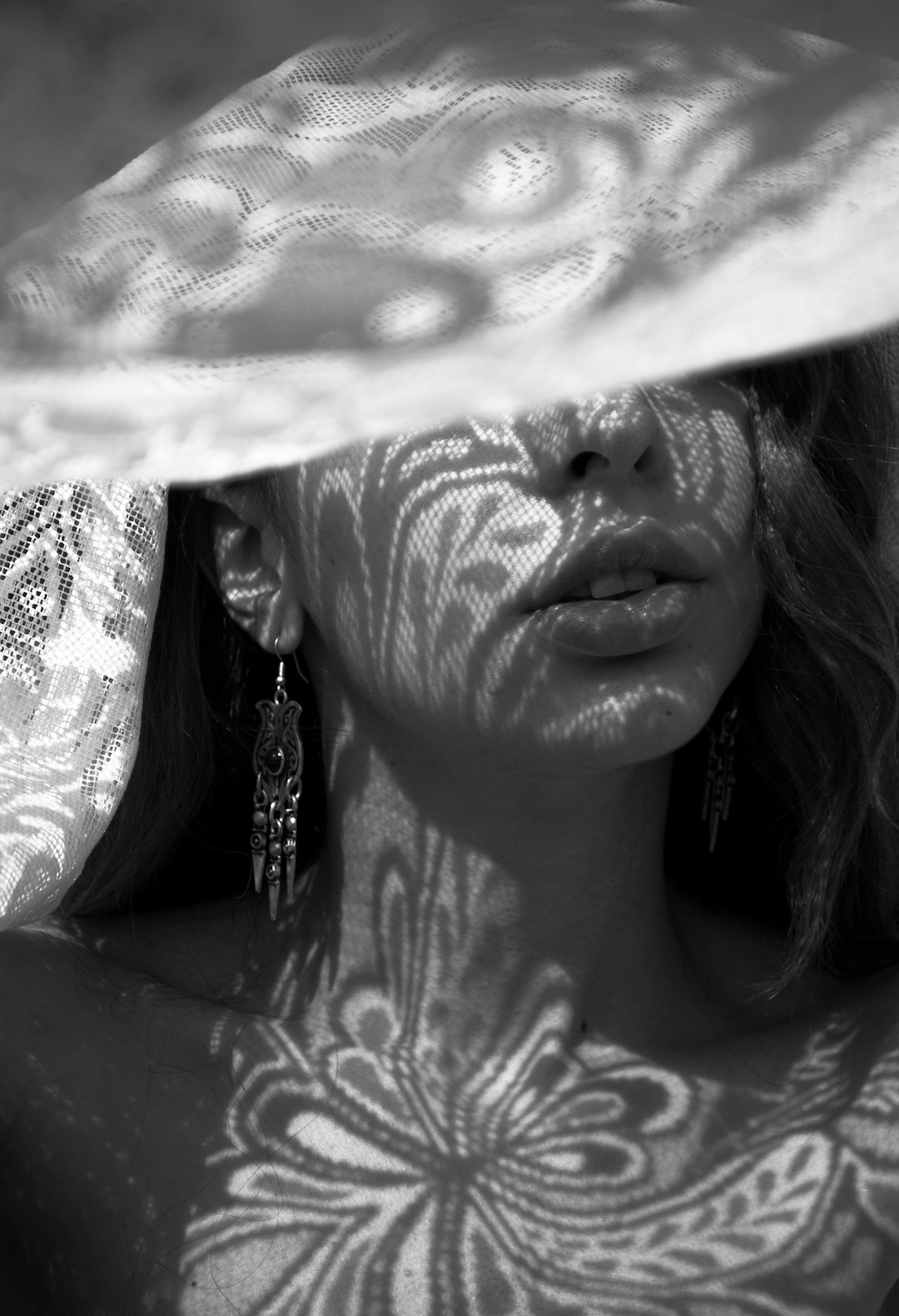 grayscale photography of woman using a floral lace cloth as cover on her face
