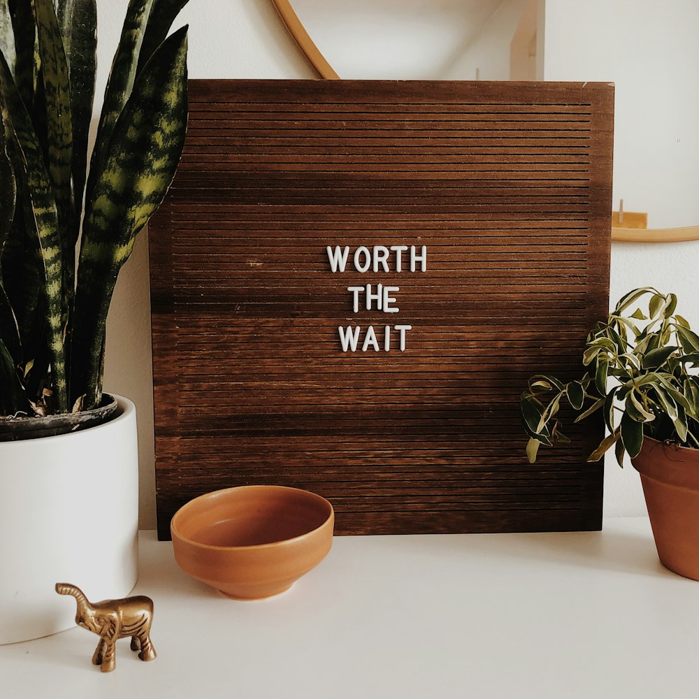 white Worth The Wait sign on brown wooden board